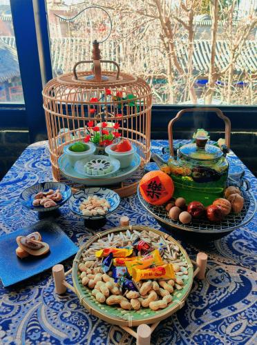a table with plates of food and a bird cage at Hotel Cote Cour Deductive Beijing - Quadrangle close to Tiananmen Square & Forbidden City & Nanluoguxiang, Walk to Wangfujing, English speaking, Free WiFi, Free Laundry, Free Wonton & Noodles with Tour ticket service, Free selfies with ancient costume in Beijing