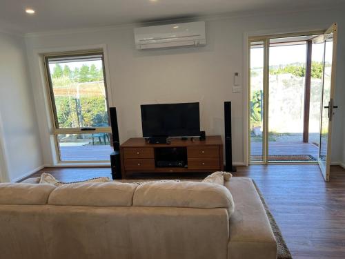 a living room with a couch and a flat screen tv at Two bedrooms Escape to Countryside Retreat in Wamboin