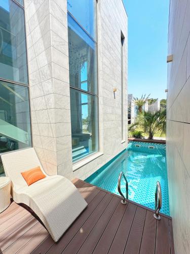 a white chair sitting on a deck next to a swimming pool at Eudaimonia Poolvilla Jeju 에다모니아 함덕풀빌라 in Jeju