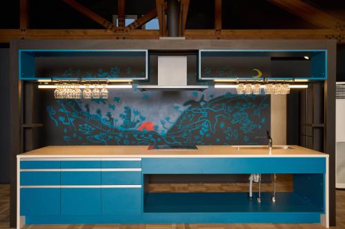 a kitchen with blue cabinets and a painting on the wall at 岬の湯しゃこたんの宿 フロリダ in Irika