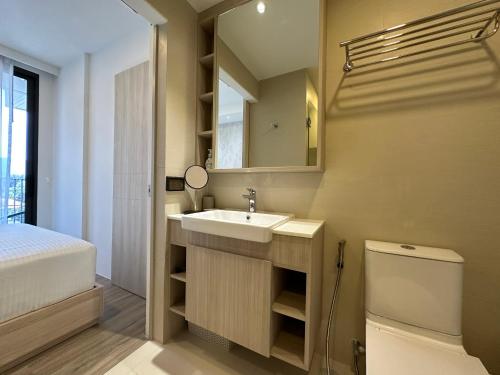 une salle de bain avec un lavabo, des toilettes et un miroir dans l'établissement 2 BD Skypark Condo, à Laguna Phuket
