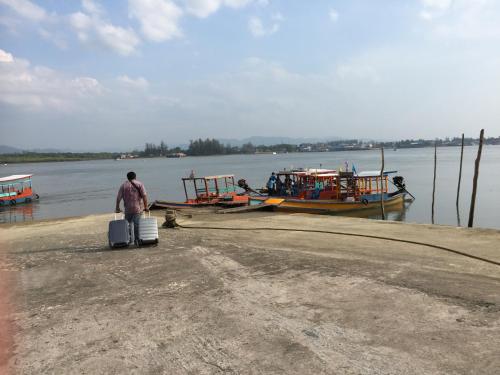 a man with a suitcase and two boats in the water at Paradis Villa B3 in Ko Kho Khao