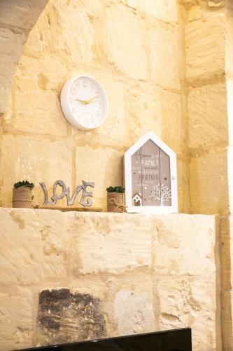 a clock on the side of a wall with some plants at Valletta City Suites in Valletta