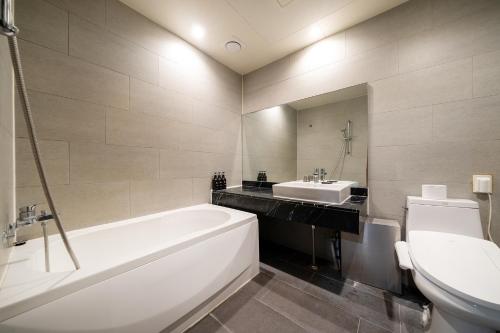 a bathroom with a tub and a sink and a toilet at Sopoong Hotel Incheon in Incheon