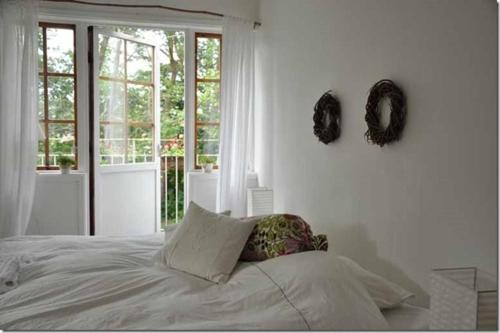 a white bedroom with a bed and a window at B&B Åvägen in Åhus