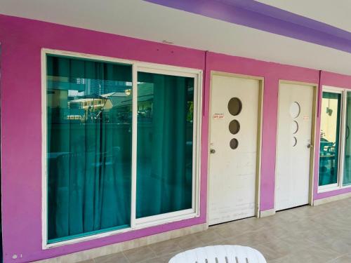 a purple wall with glass doors and a white chair at Best Bella Pattaya in Pattaya North