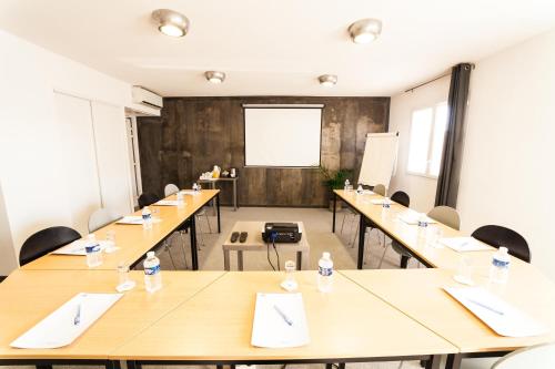 a large room with tables and chairs and a whiteboard at The Originals City, Hôtel Les Dômes, Perpignan Sud Saleilles in Perpignan