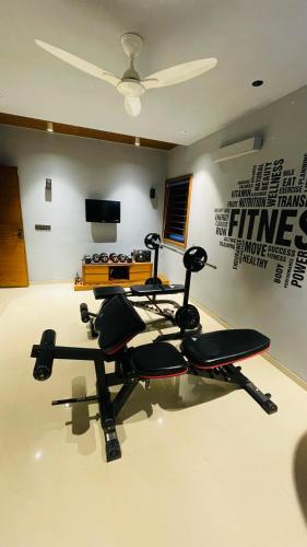 a room with a gym with a bench and a television at Nisarg’s stays in Ahmedabad