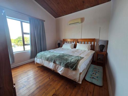 a bedroom with a bed and a large window at Reefteach Lodge in Sodwana Bay