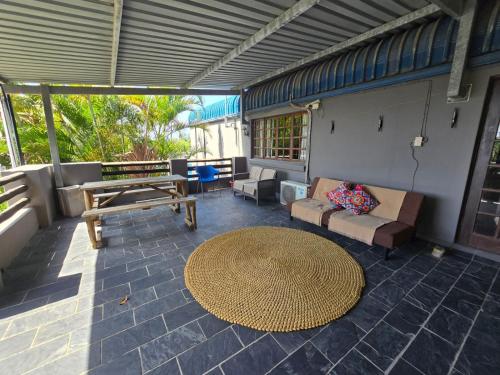 a patio with a couch and a table at Reefteach Lodge in Sodwana Bay