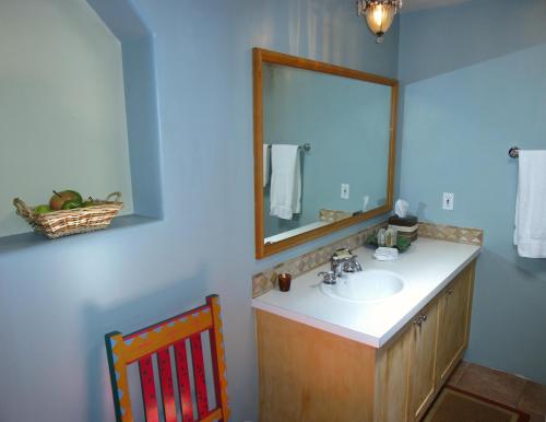 a bathroom with a sink and a mirror and a chair at Casa de Tres Lunas/House of Three Moons in Santa Fe