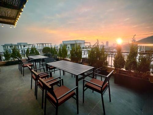 a group of tables and chairs on a balcony with a sunset at Palazzo Luxury Villa 950m2, 7 bedrooms, Pickleball court, swimming pool in Ha Long