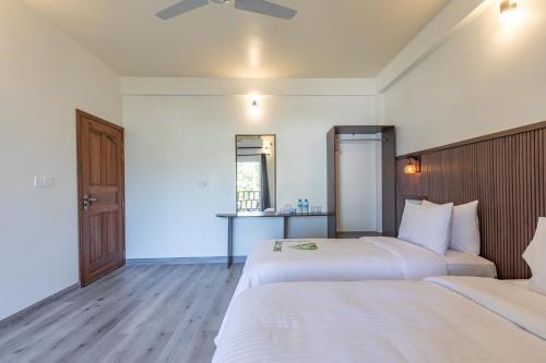 a bedroom with two beds and a table at Dhoadhi Beach Maldives in Omadhoo