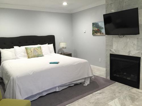 a bedroom with a bed with a fireplace and a flat screen tv at Beach Bungalow Inn and Suites in Morro Bay