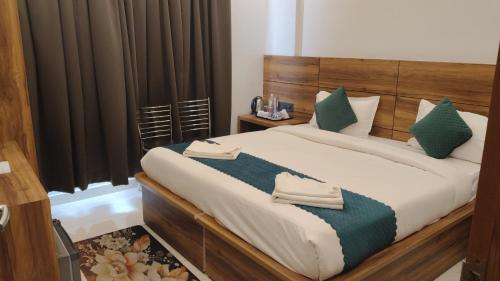 a bedroom with a large bed with green pillows at Hotel Vaidik Ganga in Rishīkesh