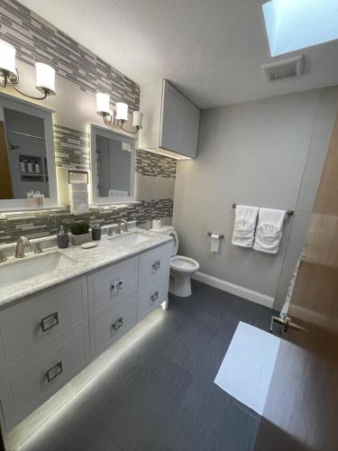 a bathroom with a sink and a toilet and a mirror at Heated pool at Persimmon Retreat in West Palm Beach