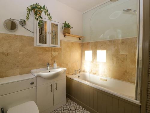 a bathroom with a sink and a bath tub at Holly Cottage in Malvern Wells
