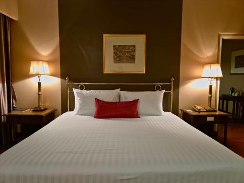 a bedroom with a white bed with a red pillow at Loei Palace Hotel in Loei