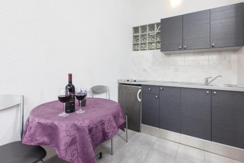uma cozinha com uma mesa roxa com copos de vinho em Apartments Smiljka em Tučepi