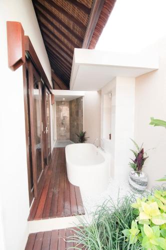 a bathroom with a bath tub on a wooden deck at Villa Puspa in Tanah Lot
