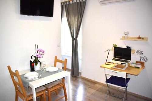 a dining room with a table and a laptop on a desk at Apartman ''Nicole'' in Pula