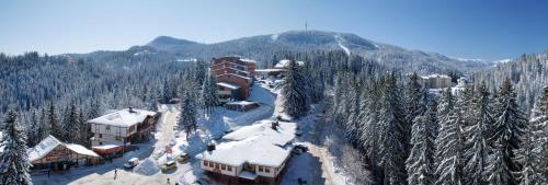 una estación de esquí con edificios cubiertos de nieve y una montaña en Hotel Prespa, en Pamporovo