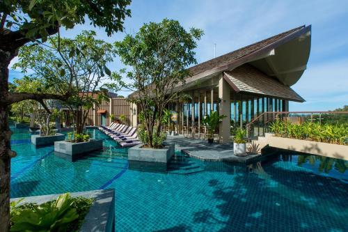 a swimming pool with chairs and a building at Mandarava Resort and Spa, Karon Beach in Karon Beach