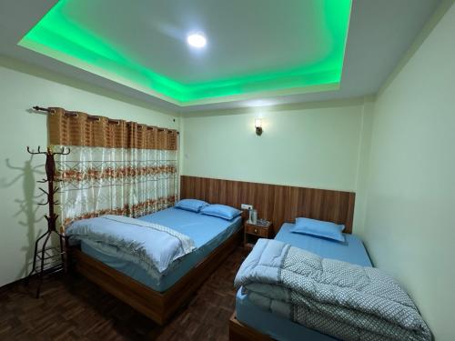 two beds in a room with a green ceiling at Dorje Homestay in Kathmandu