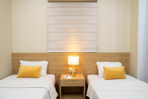 two beds with yellow pillows in a room at Shine Hue Hotel 2 in Hue