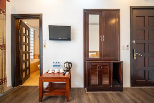 a room with a table and a tv and a door at Shine Hue Hotel 2 in Hue