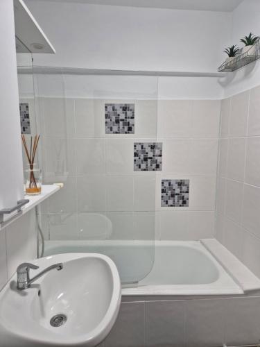une salle de bain blanche avec un lavabo et une baignoire dans l'établissement Family Residence Slănic-Moldova, à Slănic-Moldova