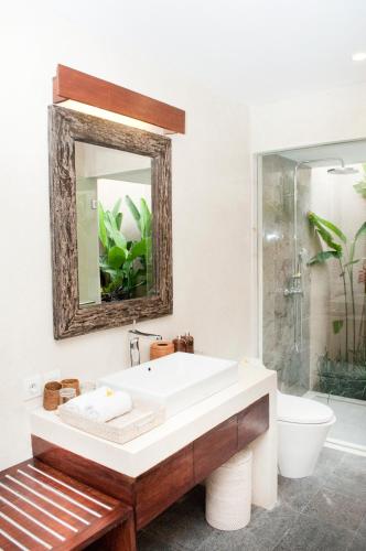 a bathroom with a tub and a toilet and a mirror at Villa Puspa in Tanah Lot