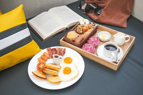 a table with a plate of breakfast food and a book at veHaa BOUTIQUE HOTEL in Phnom Penh