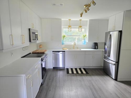 a kitchen with white cabinets and stainless steel appliances at 904 Nomad's Nest Mid-Century modern entertainment home with cabin vibes, 2 MEGA gamerooms, pingpong, pooltable, gym, patio in Jacksonville