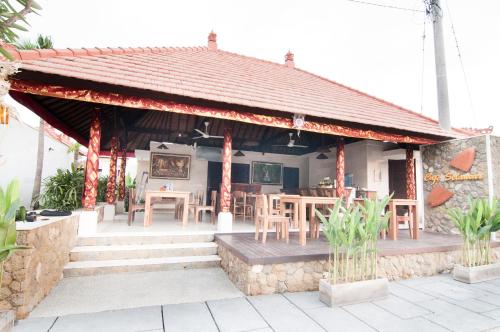 a pavilion with tables and chairs in a building at Villa Puspa in Tanah Lot