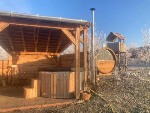 a wooden building with a hot tub in a field at Erdősmecskei sváb vendégházak és Jurtaszállás in Erdősmecske