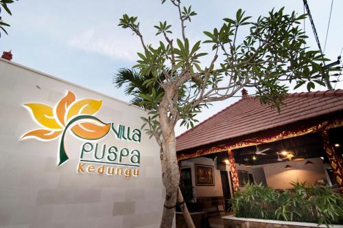 a sign for a restaurant with a tree in front of it at Villa Puspa in Tanah Lot
