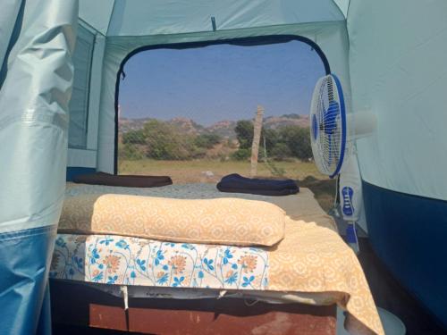 a tent with a bed and a fan in it at Hampi One Love in Hampi