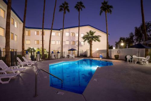 a swimming pool in front of a building with palm trees at Days Inn & Suites by Wyndham Mesa Near Phoenix in Mesa