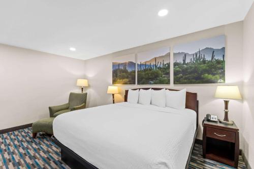 a hotel room with a large bed and a chair at Days Inn & Suites by Wyndham Mesa Near Phoenix in Mesa