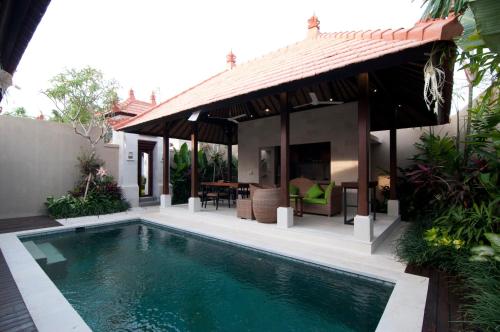 a villa with a swimming pool and a house at Villa Puspa in Tanah Lot