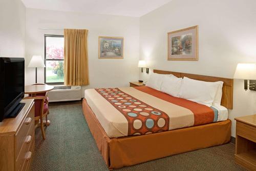 a hotel room with a bed and a flat screen tv at Super 8 by Wyndham Hampshire IL in Hampshire