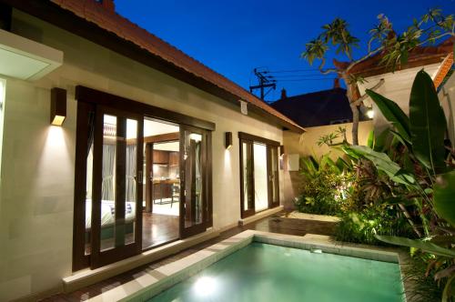 uma villa com piscina em frente a uma casa em Villa Puspa em Tanah Lot