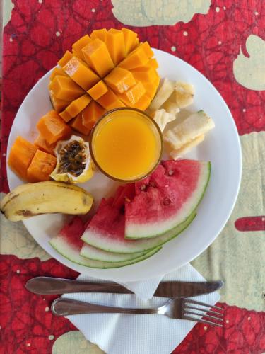 a plate of fruit and juice on a table at HOMELAND SWAHILI LODGE Nungwi Backpacker Apartments BUDGET in Nungwi