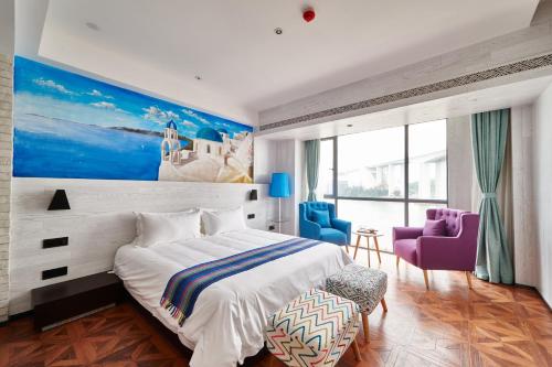 a bedroom with a large bed and two blue chairs at Aizhu Boutique Theme Hotel in Xiamen