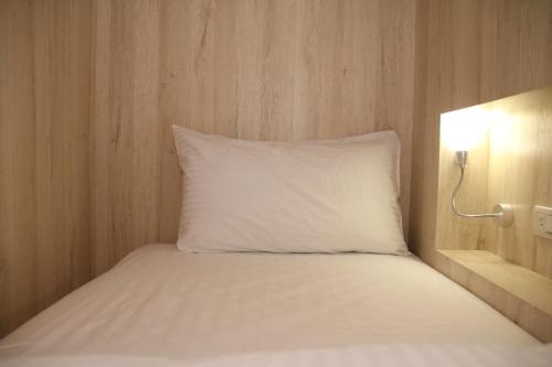 a bed with a white pillow next to a light at Jincheng Hostel in Changhua City