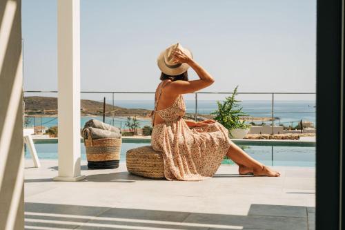 a woman sitting on a chair looking out at the ocean at Makrikythera Luxury Suites - Private Pool or Hot Tub Suites in Dhiakofti