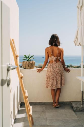 a woman standing on a ledge looking out at the ocean at Makrikythera Luxury Suites - Private Pool or Hot Tub Suites in Dhiakofti