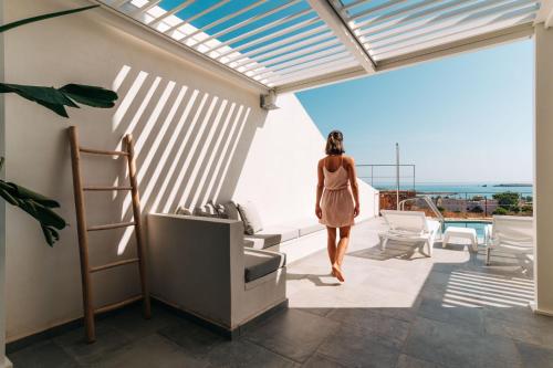 a woman walking on the balcony of a house at Makrikythera Luxury Suites - Private Pool or Hot Tub Suites in Dhiakofti