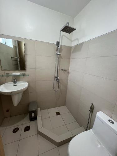a bathroom with a shower and a toilet and a sink at Lakeview Penthouse by Timothy in Tagaytay